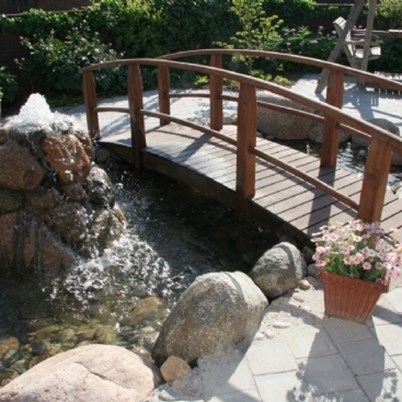 En smuk buet træbro sikrer at vandet kan krydses og nydes.